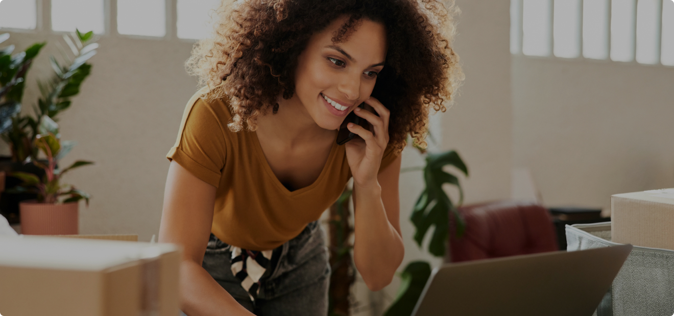 Eine Frau telefoniert und liest etwas am Laptop